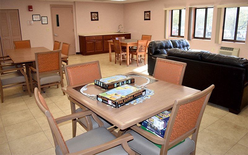 A dining table with chairs and a box of pizza in the middle.