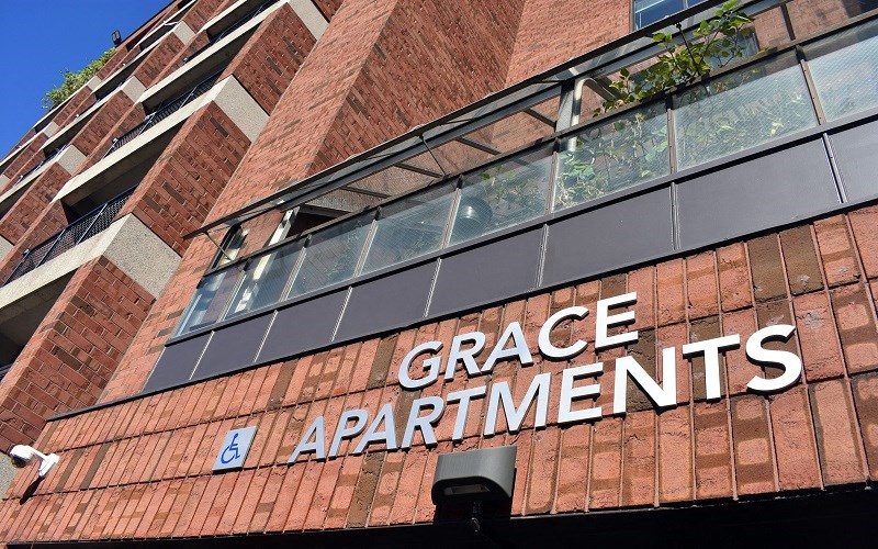A sign that says Grace Apartments is on a building.
