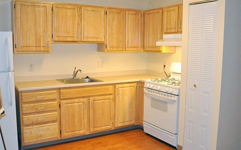 A kitchen with wooden cabinets and a white stove.