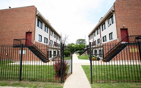 A red brick building with a black gate in front.