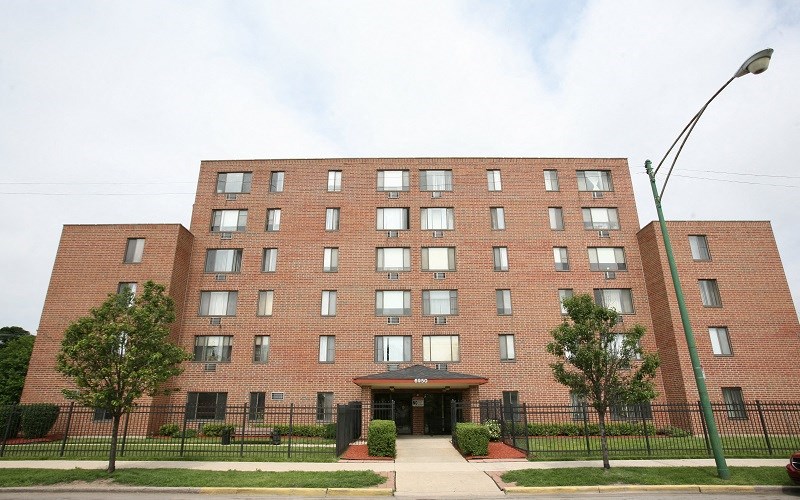 A large red brick building with a black fence in front.