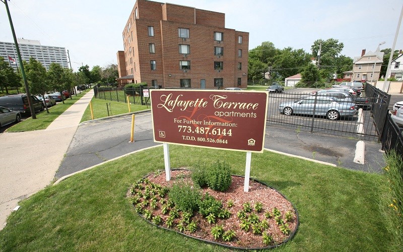 A sign for Lifayette Terrace apartments stands in front of a brick building.