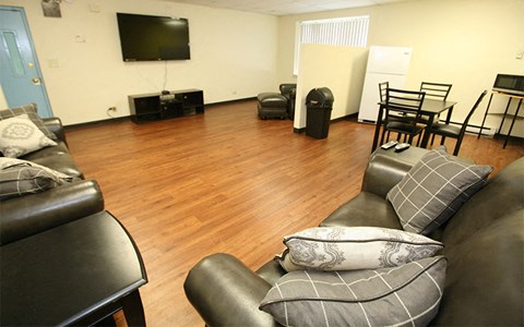A living room with a black leather couch and a television.