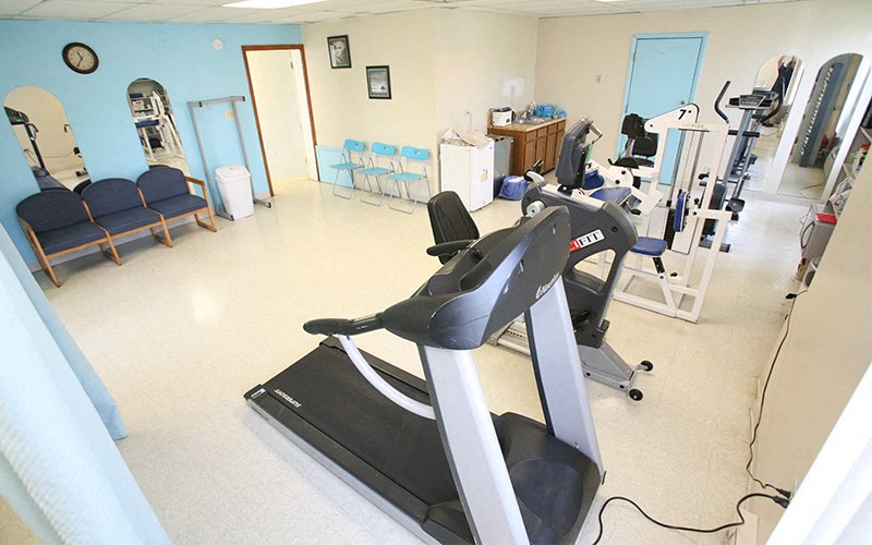 A gym with a treadmill, weights, and exercise equipment.