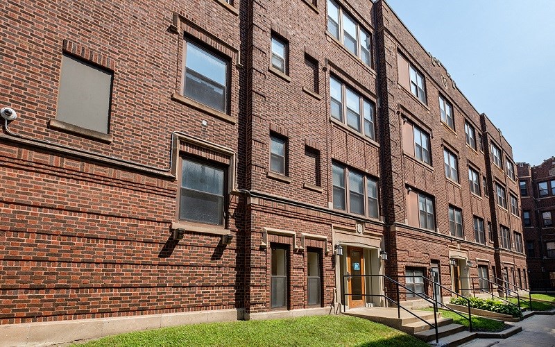A red brick building with a green lawn in front.