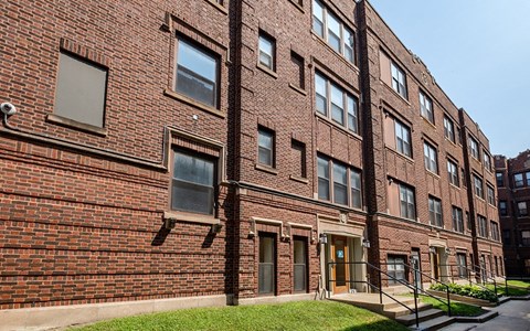 A red brick building with a green lawn in front.