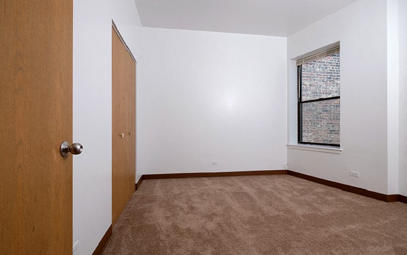 A room with a brown carpet and a wooden door.