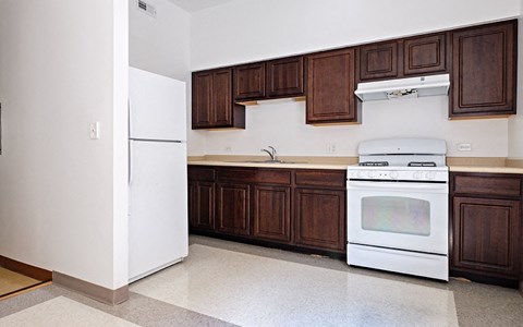 A white fridge and oven in a kitchen with brown cabinets.
