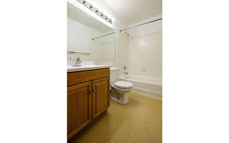 A white toilet is in a bathroom with a white tiled shower.