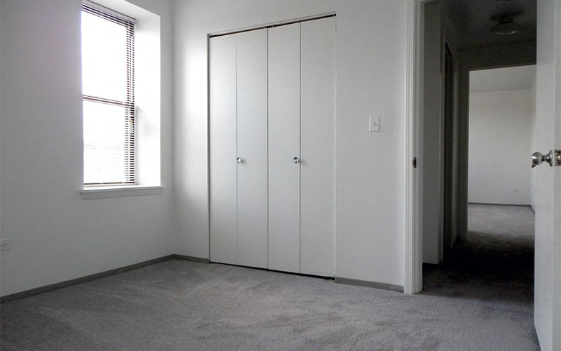 A room with a white door and a window with blinds.