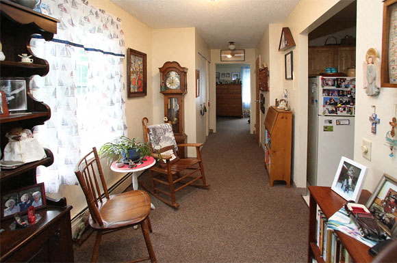 A living room with a brown carpet and a wooden chair.