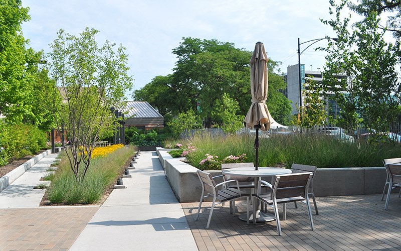 A patio with a table and chairs and a brown umbrella.