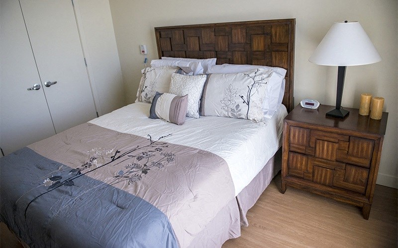 A bed with a white comforter and a wooden headboard.