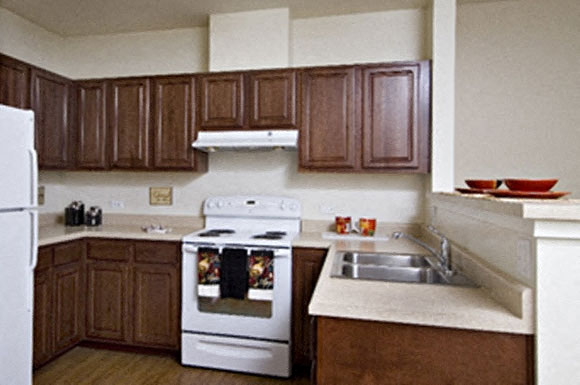 A kitchen with brown cabinets and a white stove top oven.