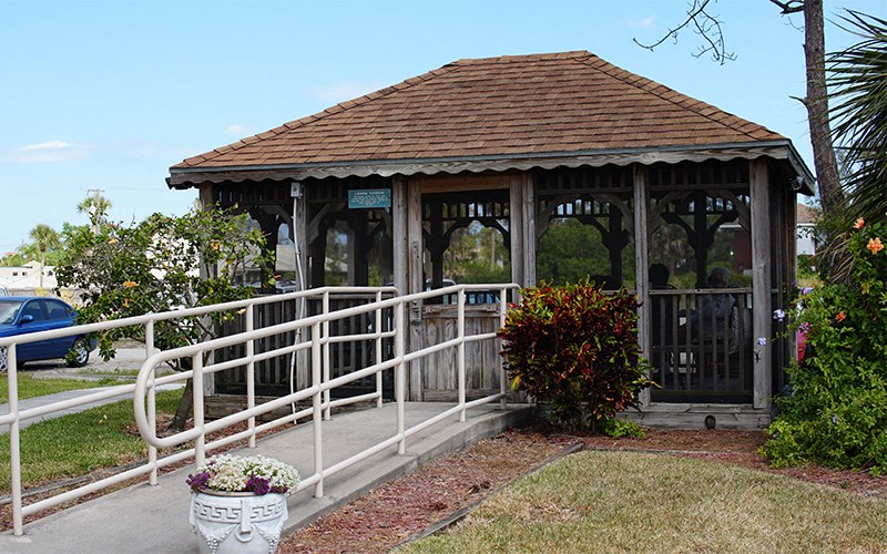 a gazebo in a park with a white fence