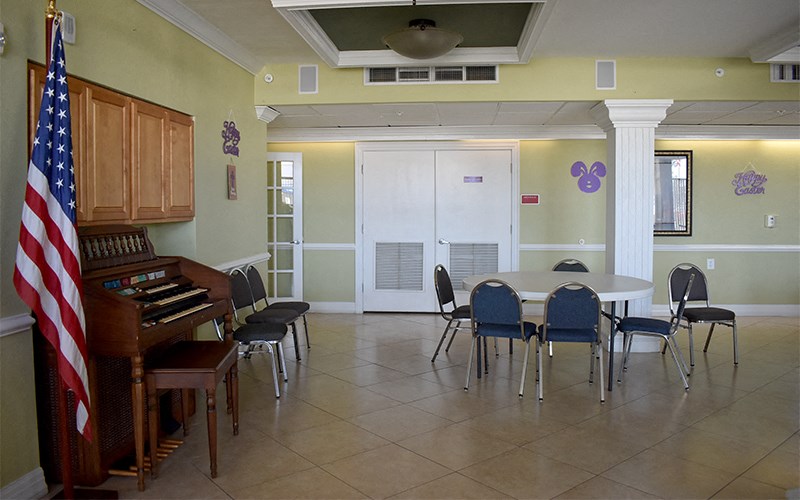 a dining room with a piano and a table and chairs and an flag