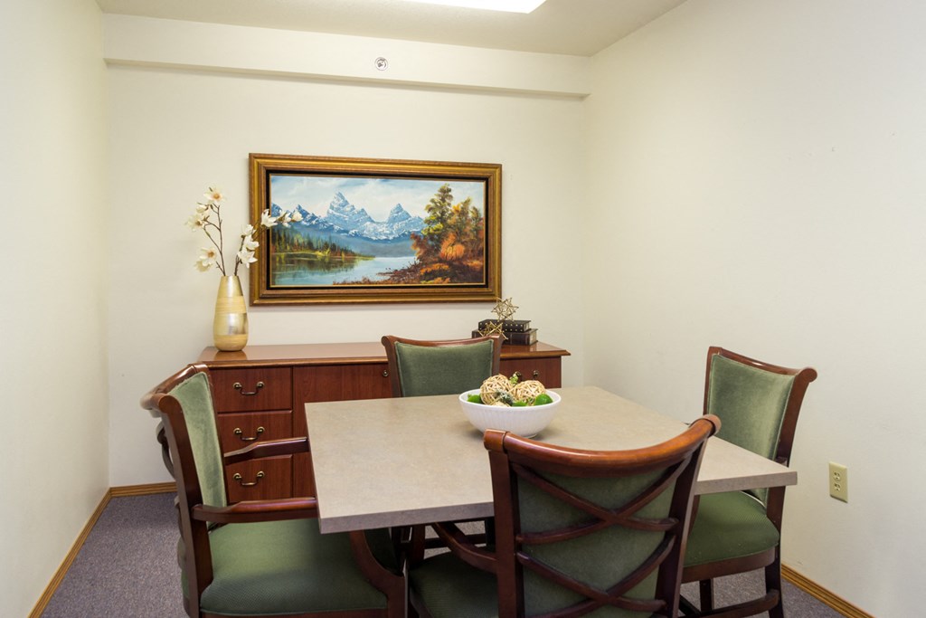 a dining room with a table and chairs and a painting on the wall