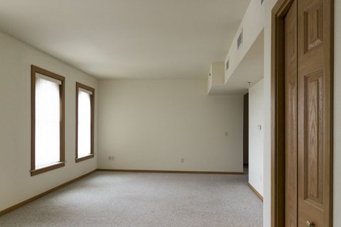 an empty room with a door and two windows