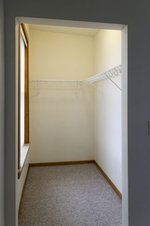 a room with a closet and a window and a clothes rack