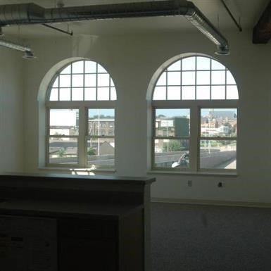 an empty room with two large windows and a counter