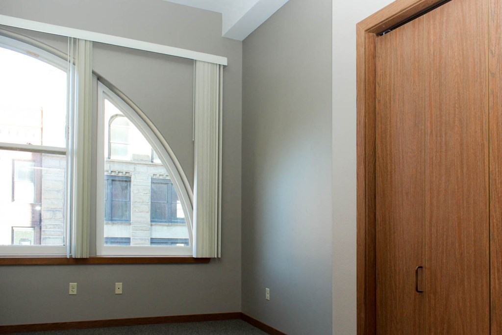 an empty room with a large window and a wooden door