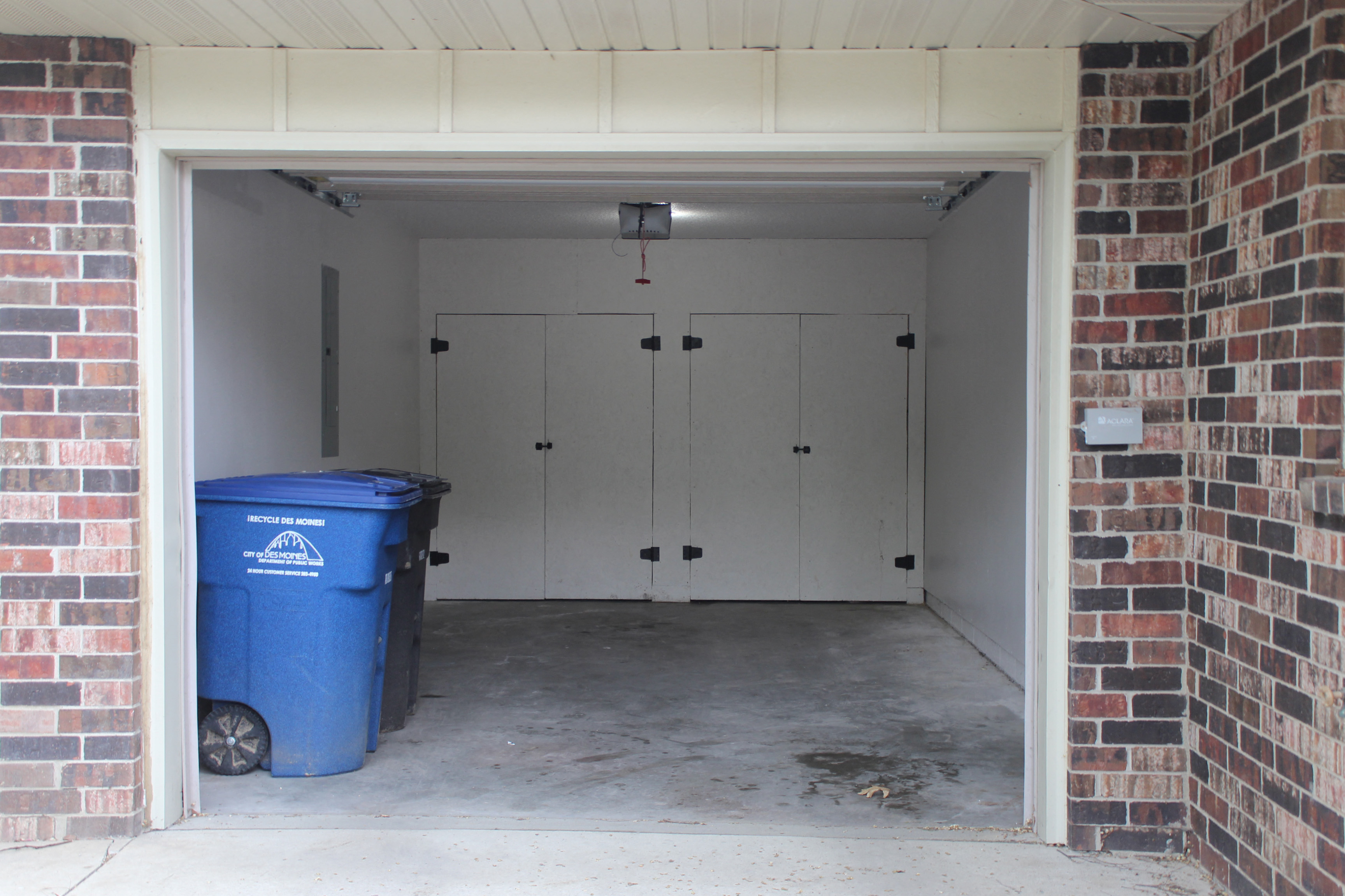 a blue trash can in a garage door with white doors