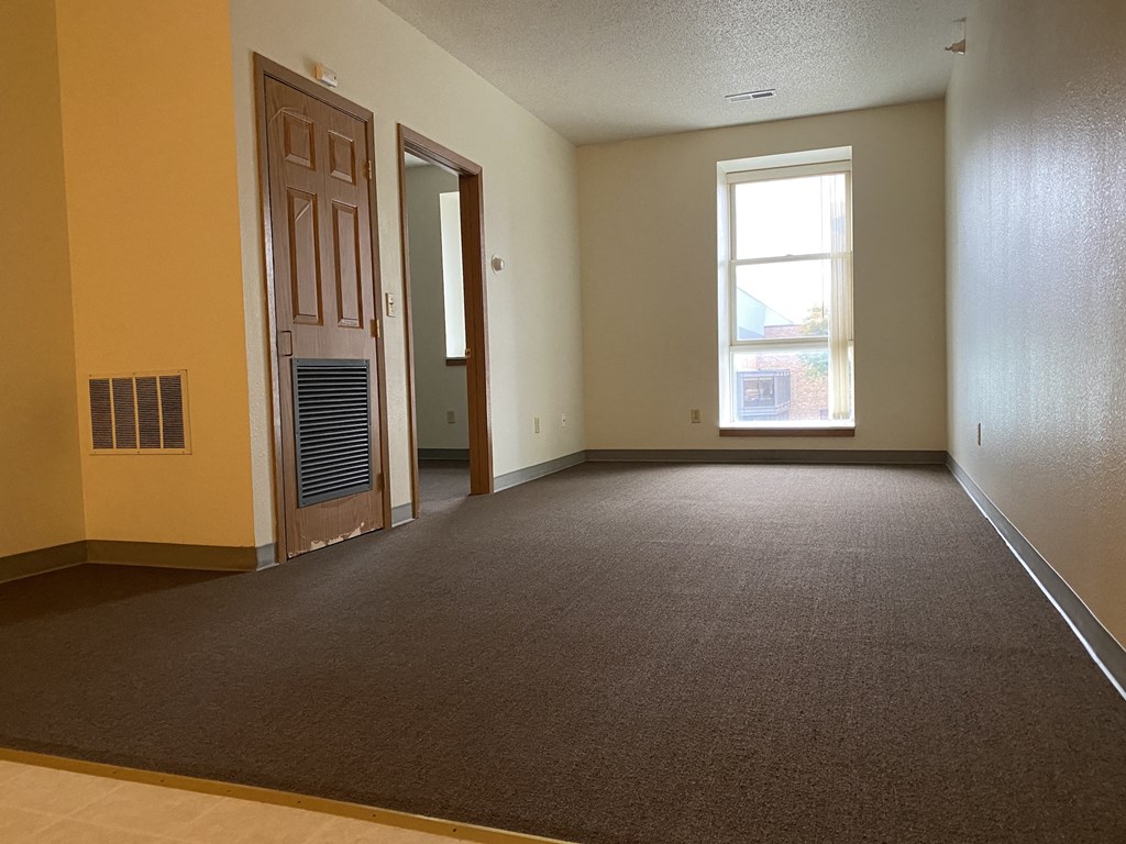 an empty living room with a door and a window
