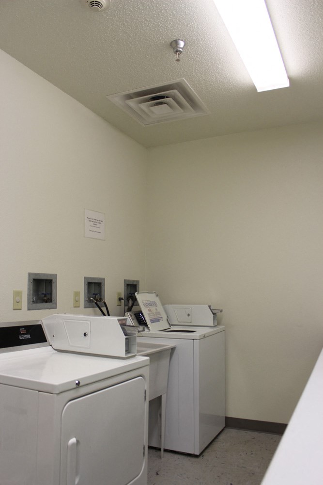 an empty laundry room with four washers and dryers