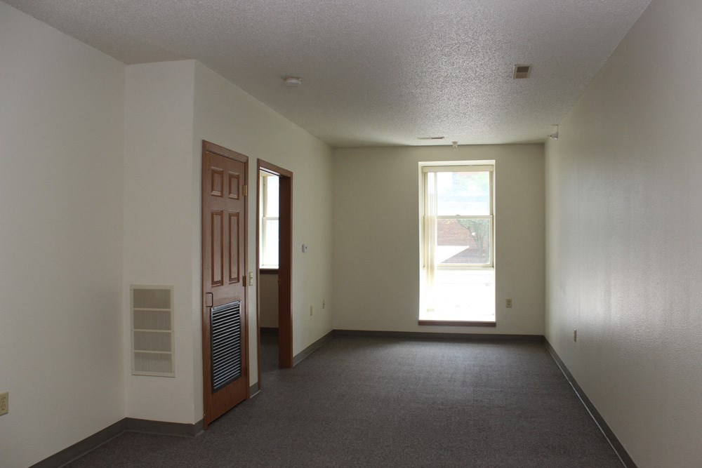 an empty living room with a door and a window