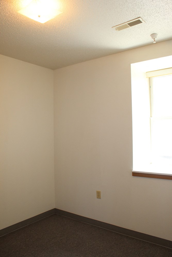an empty room with a window and a ceiling fan