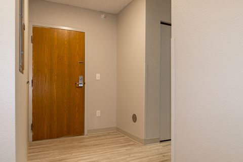 an empty room with a wooden door and a white wall