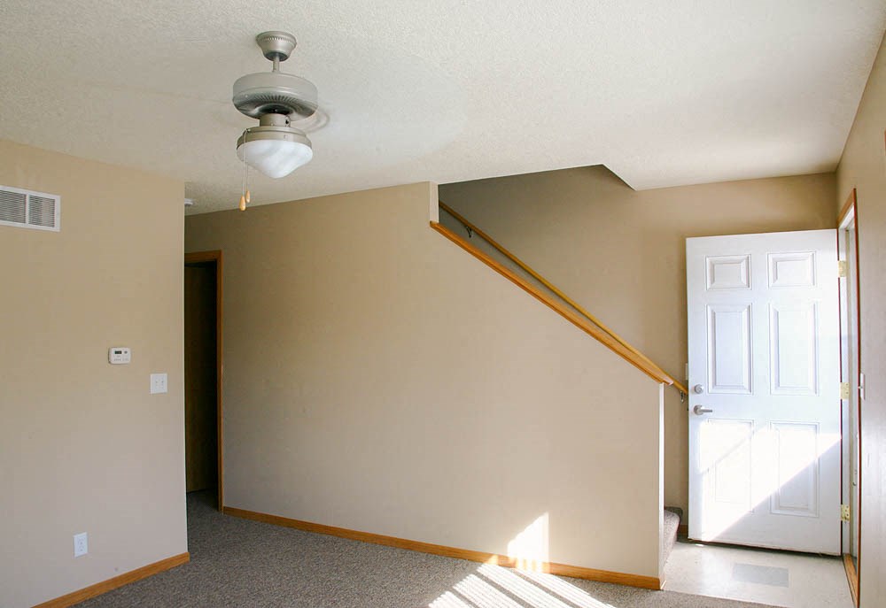 an empty room with a door and a ceiling fan