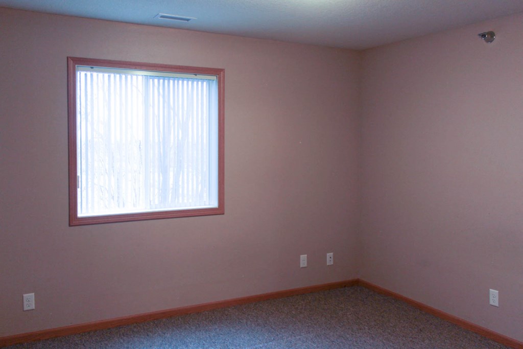 a bedroom with a window and a carpeted floor