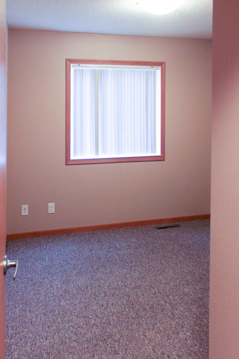 an empty room with a window and a carpeted floor