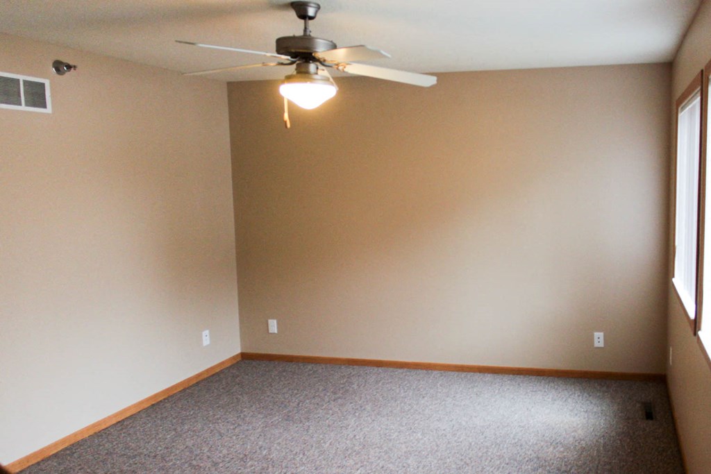 a living room with a ceiling fan and a carpet