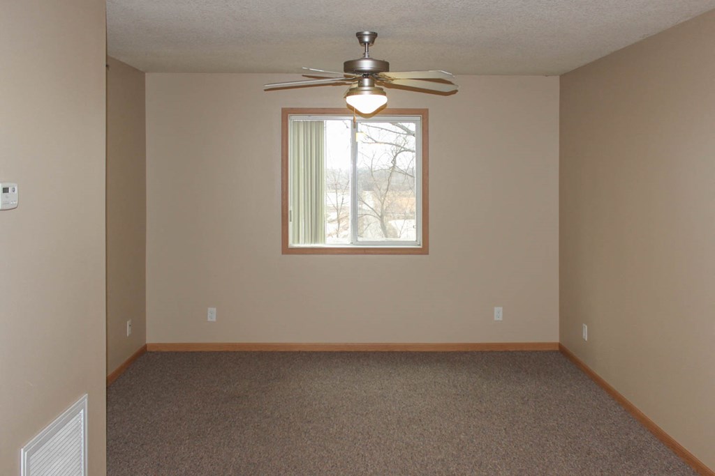 a empty living room with a ceiling fan and a window