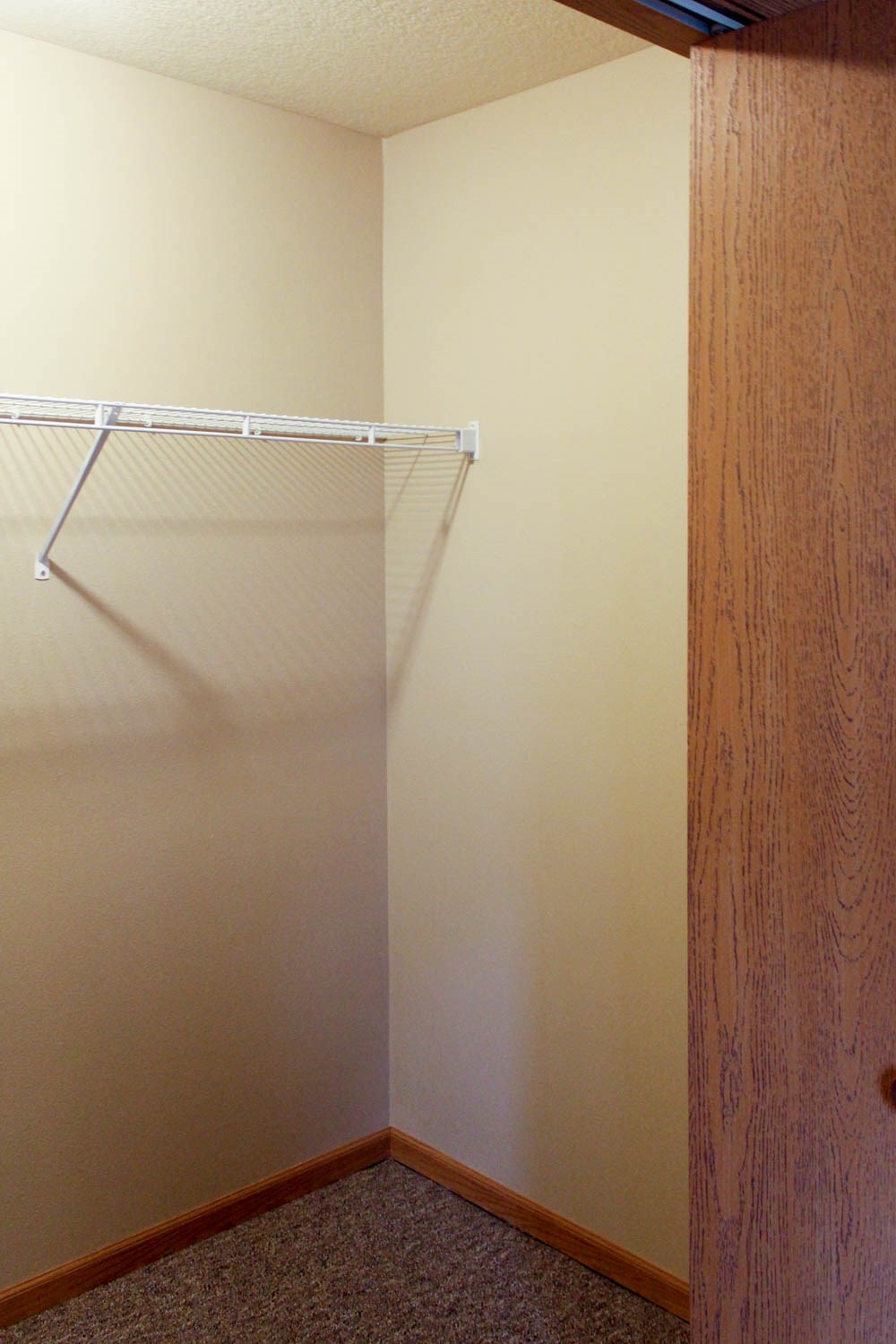a walk in closet with a wooden door and a white wall