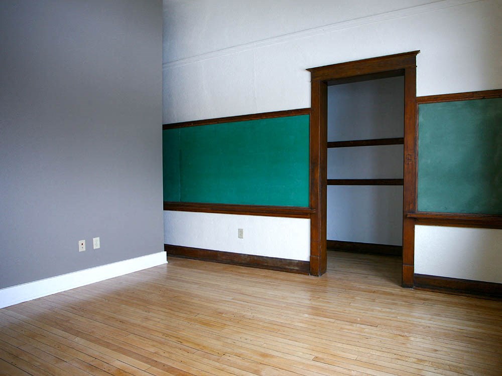 an empty room with a green wall and a wooden floor