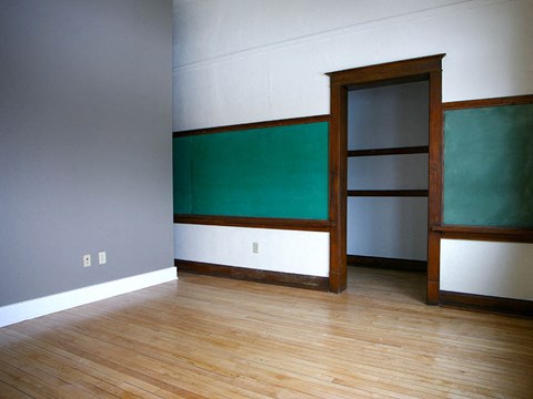 an empty room with a green wall and a wooden floor