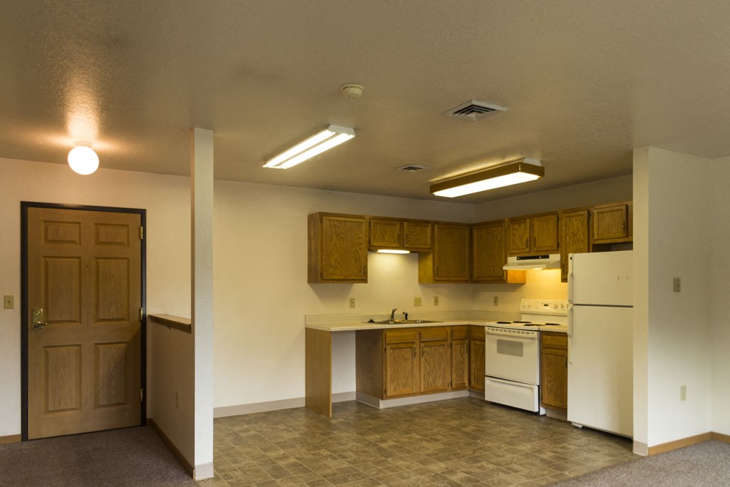 an empty kitchen with white appliances and wooden cabinets