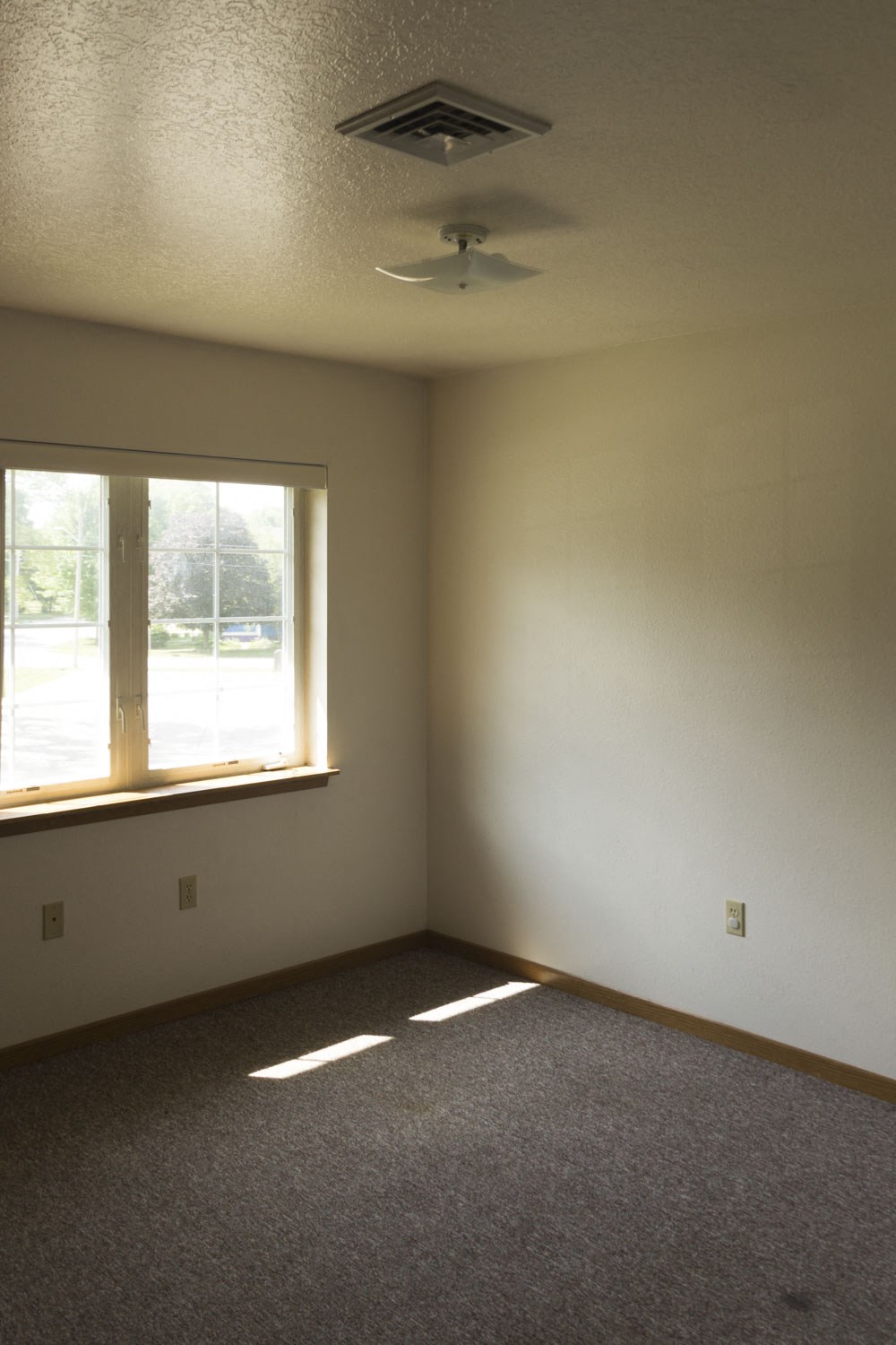 an empty room with a window and a ceiling fan