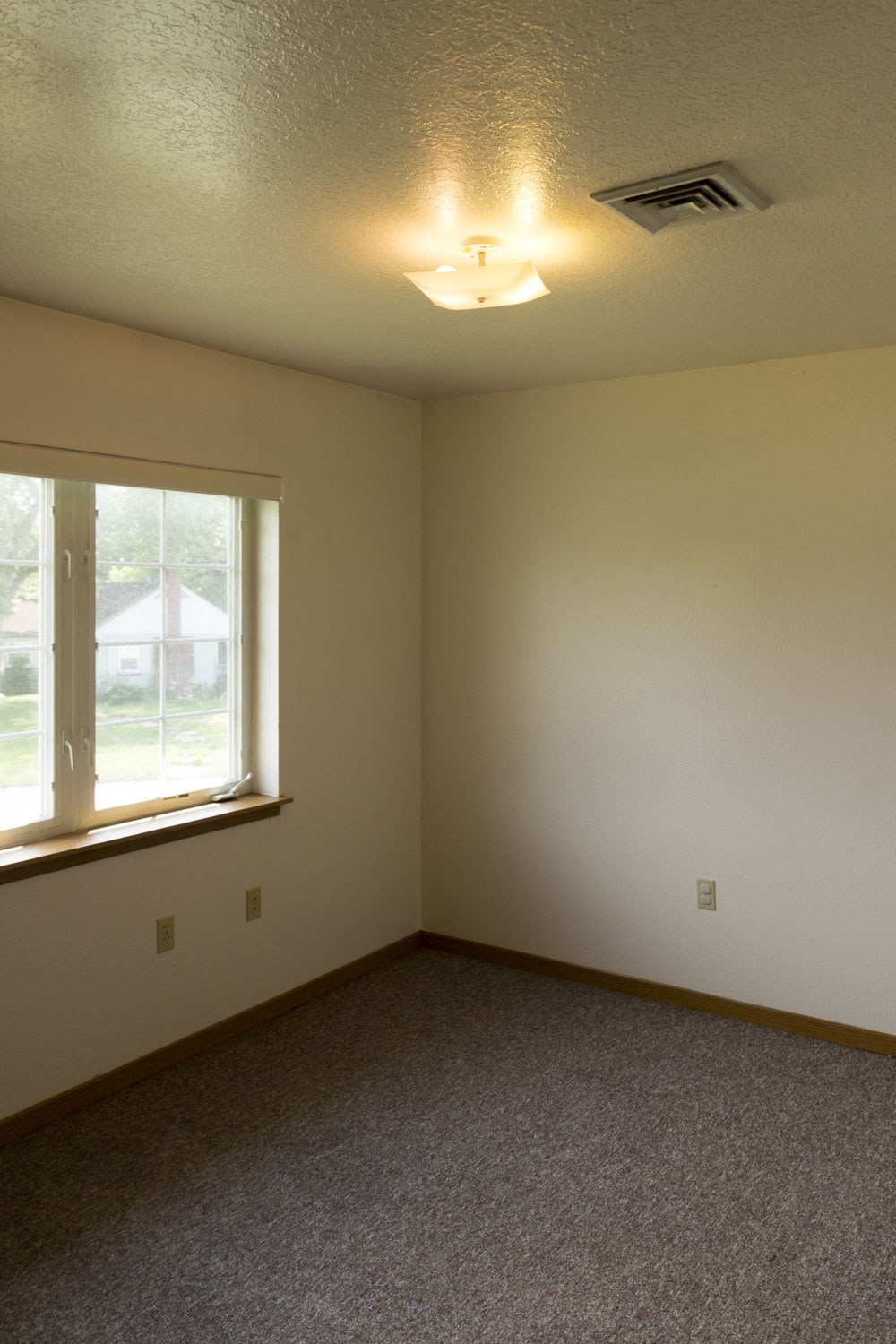 an empty living room with a window and a ceiling fan
