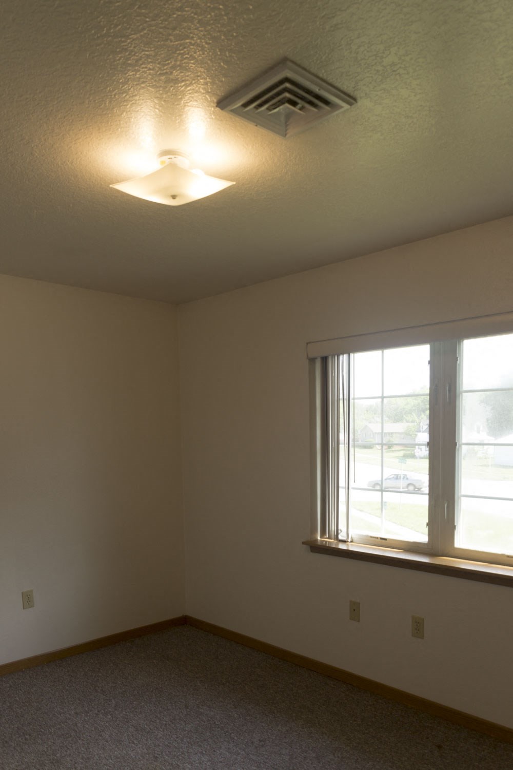 an empty room with a window and a ceiling fan