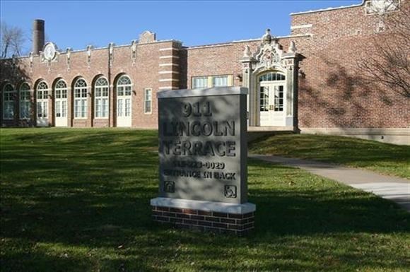 a sign in the grass in front of a brick building