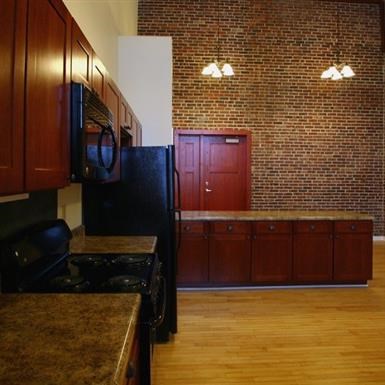 a kitchen with a black refrigerator and a brick wall