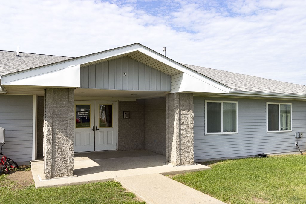 the front of a gray house with a white door