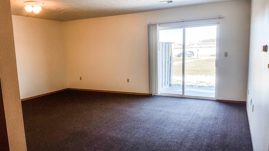 an empty living room with a door to a patio