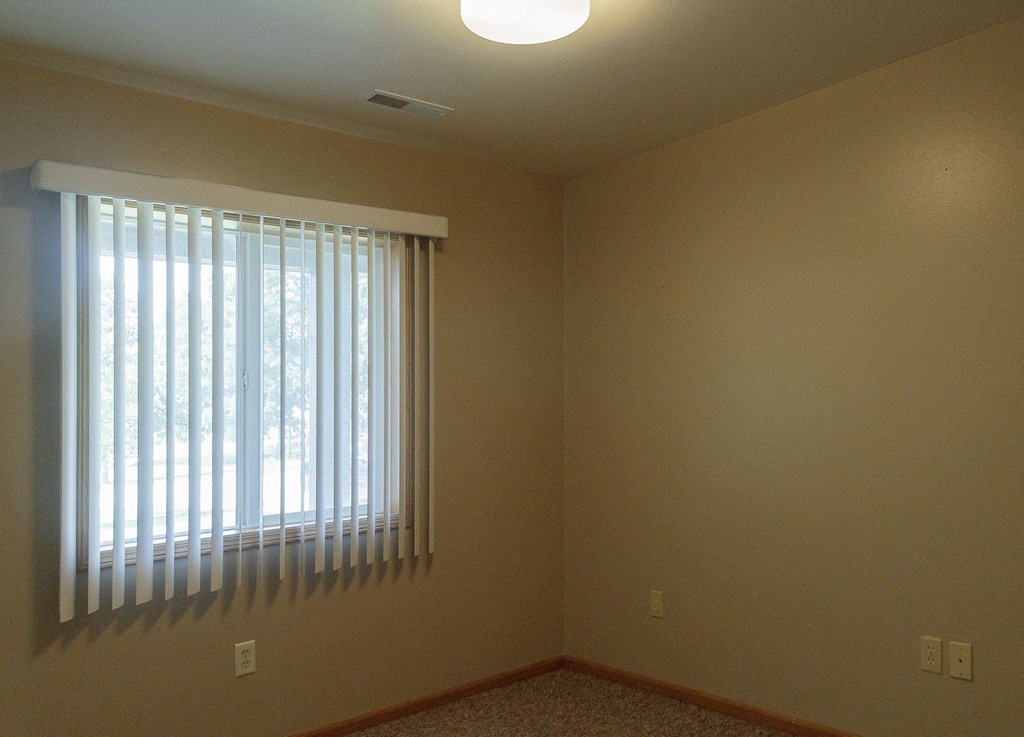 the corner of a room with a window and blinds