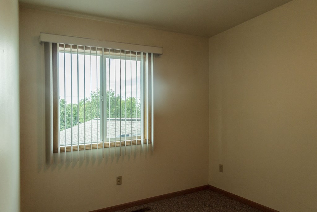 an empty room with a window with blinds