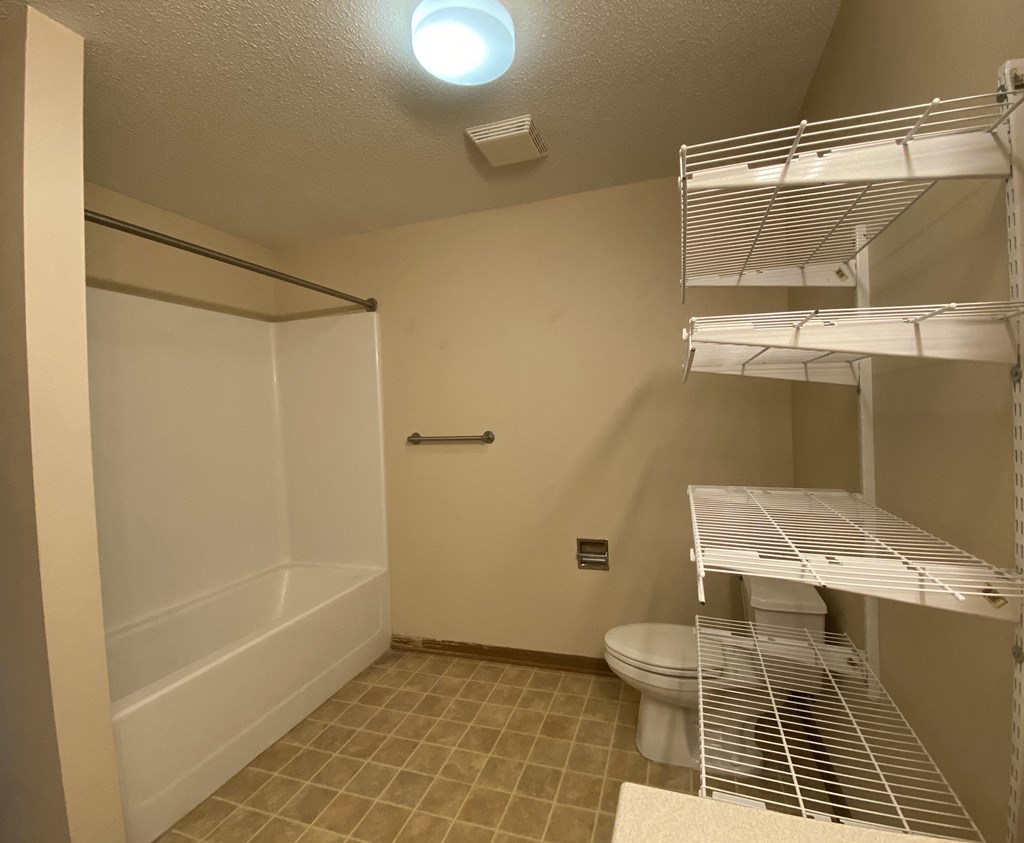 a bathroom with a toilet and a shower and a closet
